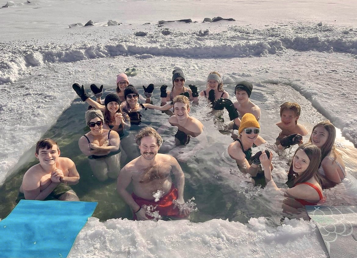 Group cold plunge in a lake ice hole, winter